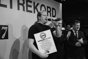 Mann mit Mikrofon und Weltrekord-Urkunde beim Silpion Kicker Cup